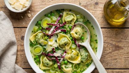 Heldere groene kruidenbouillon met tortellini en radicchio